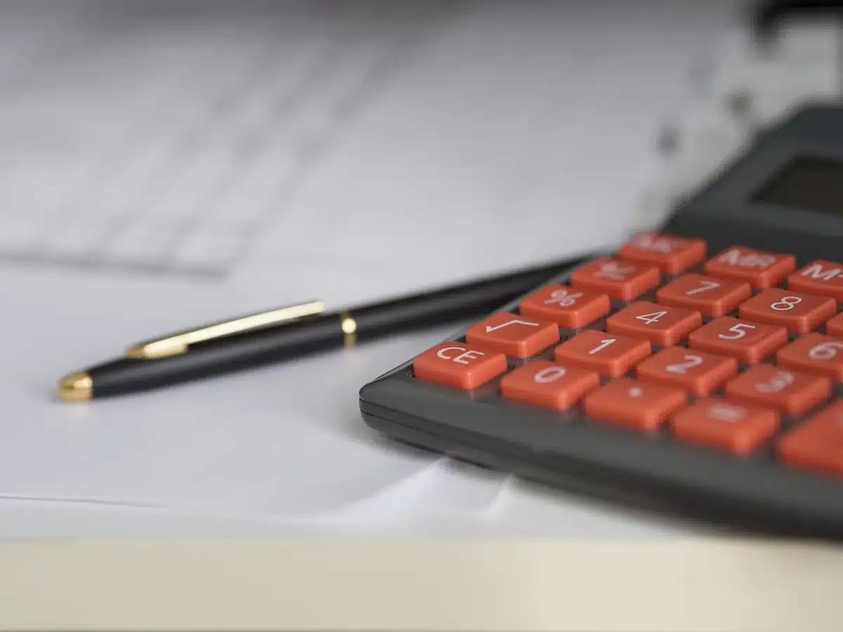 Flacon d'e‑liquide posé près de documents et d'une calculatrice