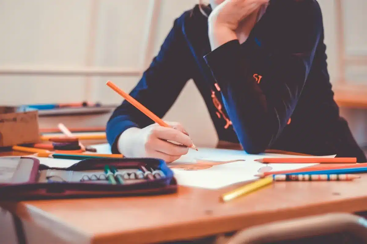 Mains anonymes tenant une cigarette électronique sur une table d'école, jour